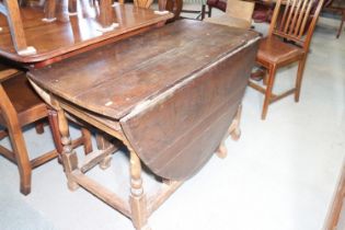 An early 18th century oak oval drop leaf gate leg dining table, fitted two drawers, on turned and