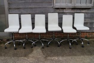 A set of six white leatherette dining chairs, on chrome castored supports