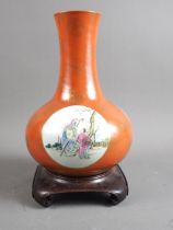 A Chinese porcelain famille rose bulbous vase, decorated three panels of figures on an orange and