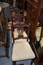 A set of six Edwardian carved walnut dining chairs with pierced splat backs and stuffed over