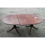 A mahogany double pedestal dining table of Georgian design with one extra leaf, on twin turned