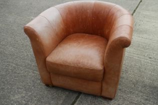 A tan leather deep seat tub shape armchair, on square taper supports