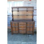 An Ercol dark elm Old Colonial dresser with three-tier plate rack over four drawers and flanking