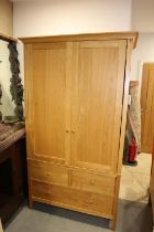 A modern oak wardrobe enclosed two doors over two small and one long drawer, on style supports,