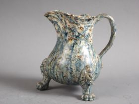 A mid 18th century agate ware cream jug, on lion mask and paw feet, 4" high