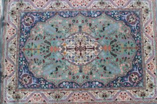 A wool pile rug of Persian design with central white medallion on a light green ground and all-