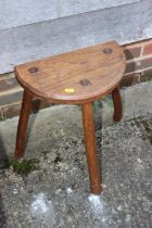 An ash and birch milking stool with semicircular seat, 13" wide x 17 1/2" high, and an early 20th