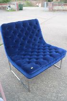 A modern low seat chair, button upholstered in a blue velvet, on chrome frame