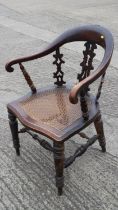 A captain's 19th century tub shape elbow chair with pierced three-splats and cane seat, on turned