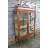 An Edwardian mahogany and inlaid display cabinet with shaped pediment over two glazed doors, on