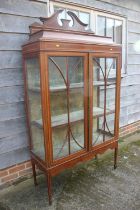 An Edwardian mahogany and inlaid display cabinet with shaped pediment over two glazed doors, on