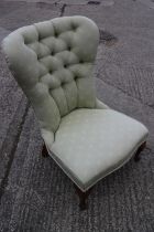 A low seat nursing chair, button upholstered in a light green fabric, on cabriole supports