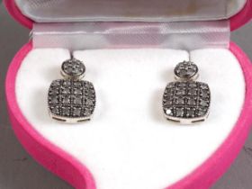 A pair of silver and diamond drop earrings