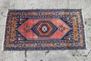 A Caucasian tribal rug with hexagonal medallion on a salmon ground and multi-borders in shades of