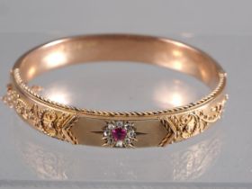 A 9ct rose gold hinged bangle, set ruby and diamonds, 2 1/2" wide, 16.9g