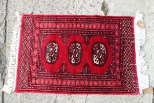 A Bokhara rug of traditional design with three guls on a red ground, 34" x 28" approx