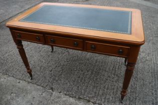 A walnut writing desk with tooled lined top, fitted three drawers, on reeded and castored supports