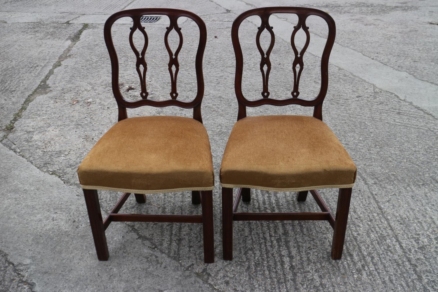 A pair of late Georgian mahogany shaped pierced twin splat dining chairs with serpentine stuffed