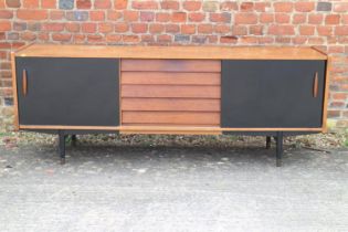 A 1960s teak and ebonised panel sliding door sideboard, fitted five centre drawers, on ebonised