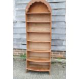 A 1930s oak bowfront arch top waterfall open bookcase, on panel end supports, 23" wide x 12" deep