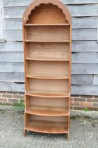 A 1930s oak bowfront arch top waterfall open bookcase, on panel end supports, 23" wide x 12" deep