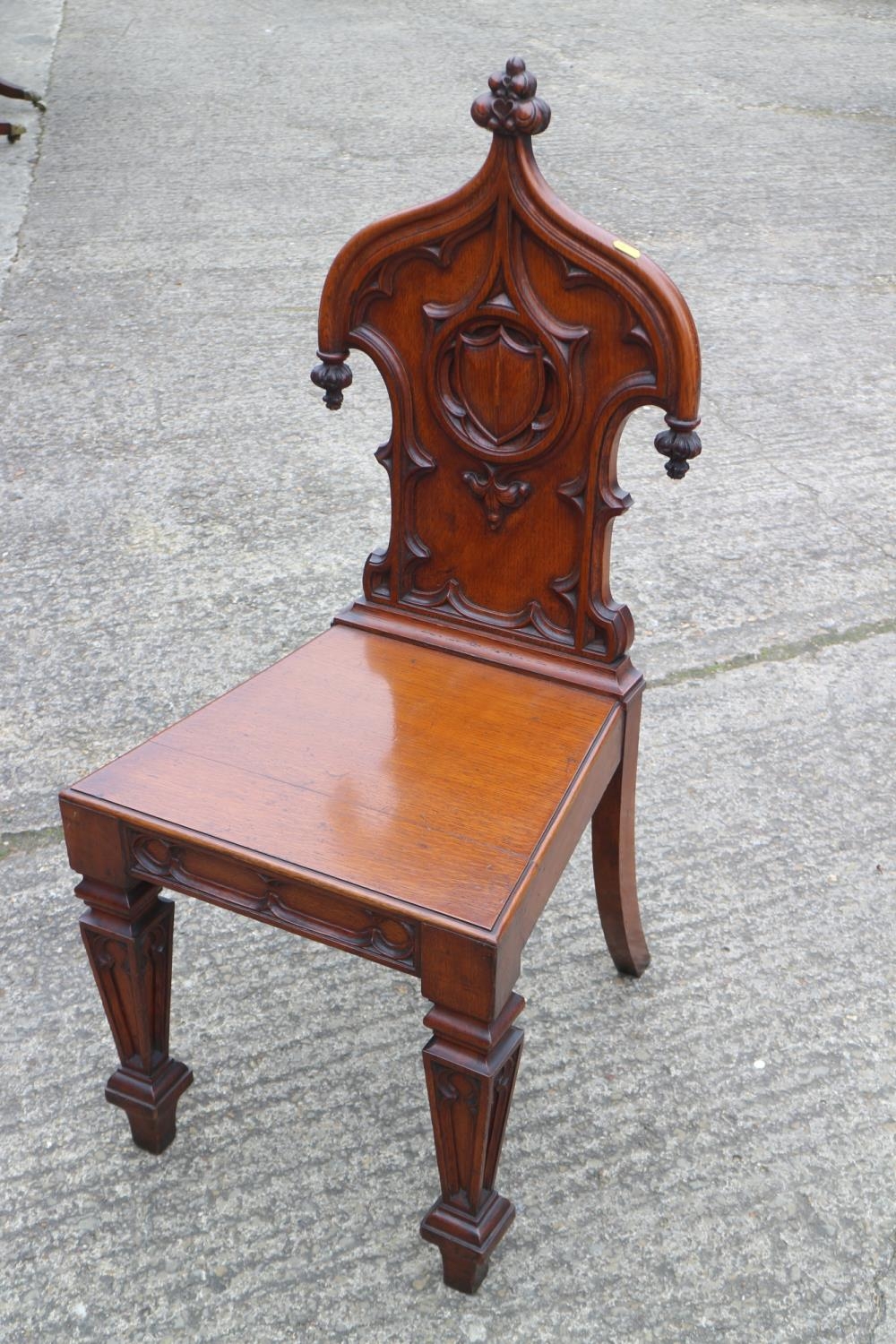A 19th century carved oak hall chair with Gothic blind fret back and panel seat, on turned supports