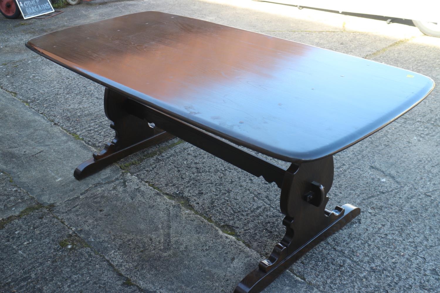 An Ercol dark elm Old Colonial refectory type fixed top dining table, on pierced panel end supports,