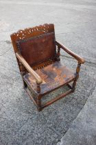 A "monk's " carved oak table/chair with leather seat, on turned and stretchered supports