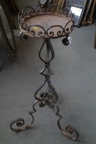 A wrought iron jardiniere stand with galleried top, on tripod scrolled supports