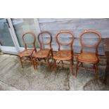 A set of four polished as walnut cane seat bedroom chairs, on turned splay supports