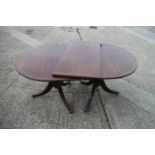 A mahogany and banded double pedestal dining table with one extra leaf, on vase turned columns and