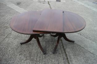 A mahogany and banded double pedestal dining table with one extra leaf, on vase turned columns and