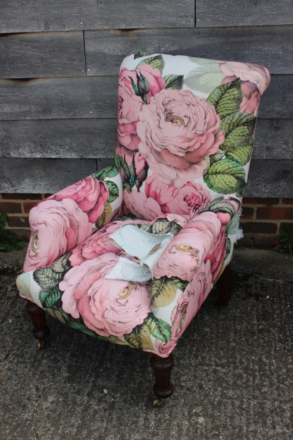 An early 20th century walnut framed low seat armchair, upholstered in a floral fabric, on turned and