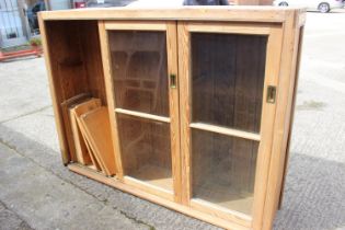 A waxed pine bookcase enclosed three sliding glazed panel doors, 68" wide x 17" deep x 51 1/2" high