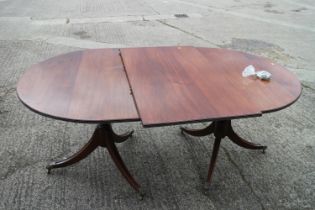 A mahogany double pedestal dining table of Georgian design with one extra leaf, on twin turned