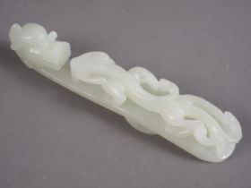 A Chinese carved pale green jade belt loop, formed as a dragon, 4 1/2" long