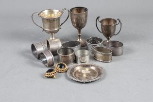 Nine assorted silver napkin rings, three silver trophies, a silver dish and a pair of gilt metal ear
