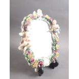 A Continental porcelain framed wall mirror with relief decoration of cherubs and flowers, 10" high