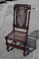 A late 17th century carved walnut side chair with oval cane back panel, cane seat and cherubim