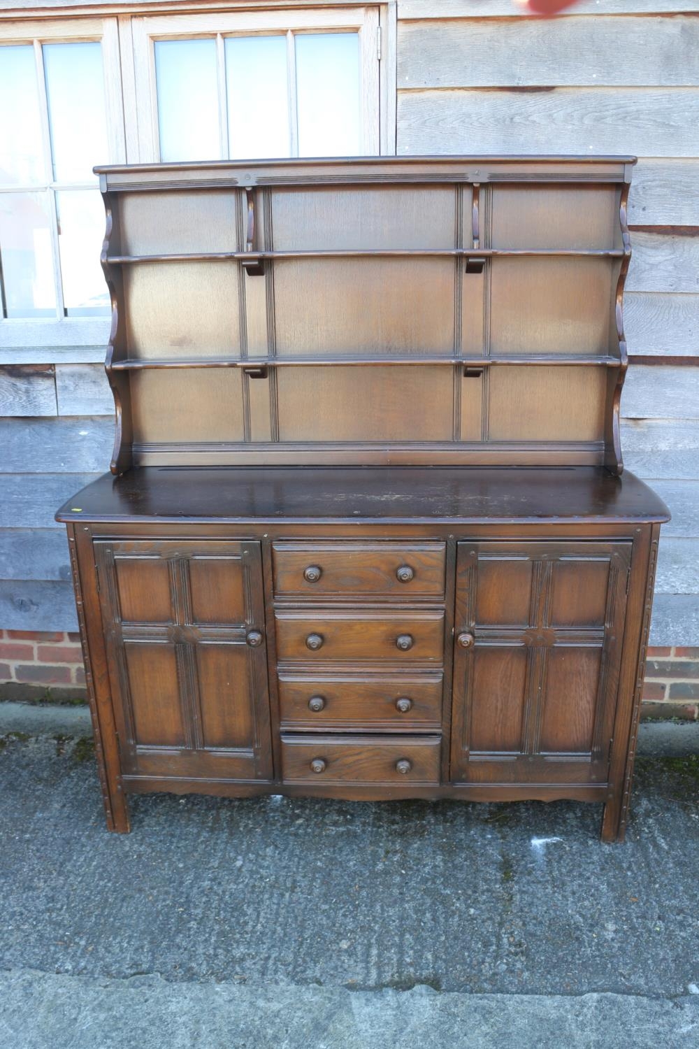 An Ercol dark elm Old Colonial dresser with three-tier plate rack over four drawers and flanking
