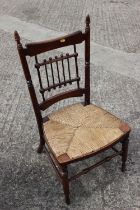 An early 20th century polished as walnut low rush envelope seat bedroom chair, on turned and