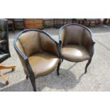 A pair of ebonised tub chairs with green leather seats, on cabriole supports