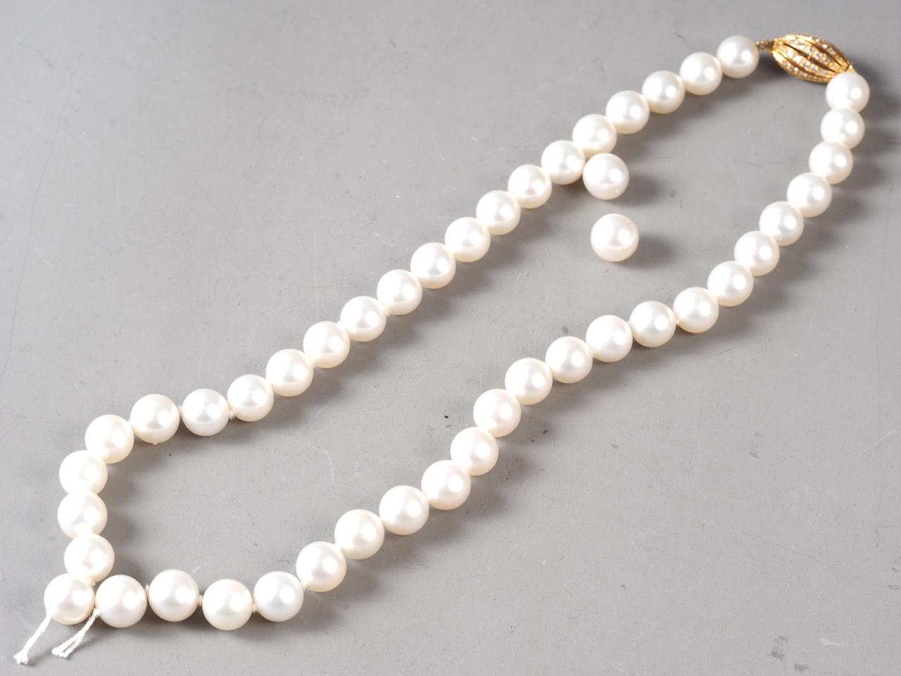 A cultured pearl single strand necklace with yellow metal, stamped 750, clasp, set diamonds,