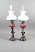 A pair of early 19th century patinated candlesticks, formed as putti, with later added ruby glass