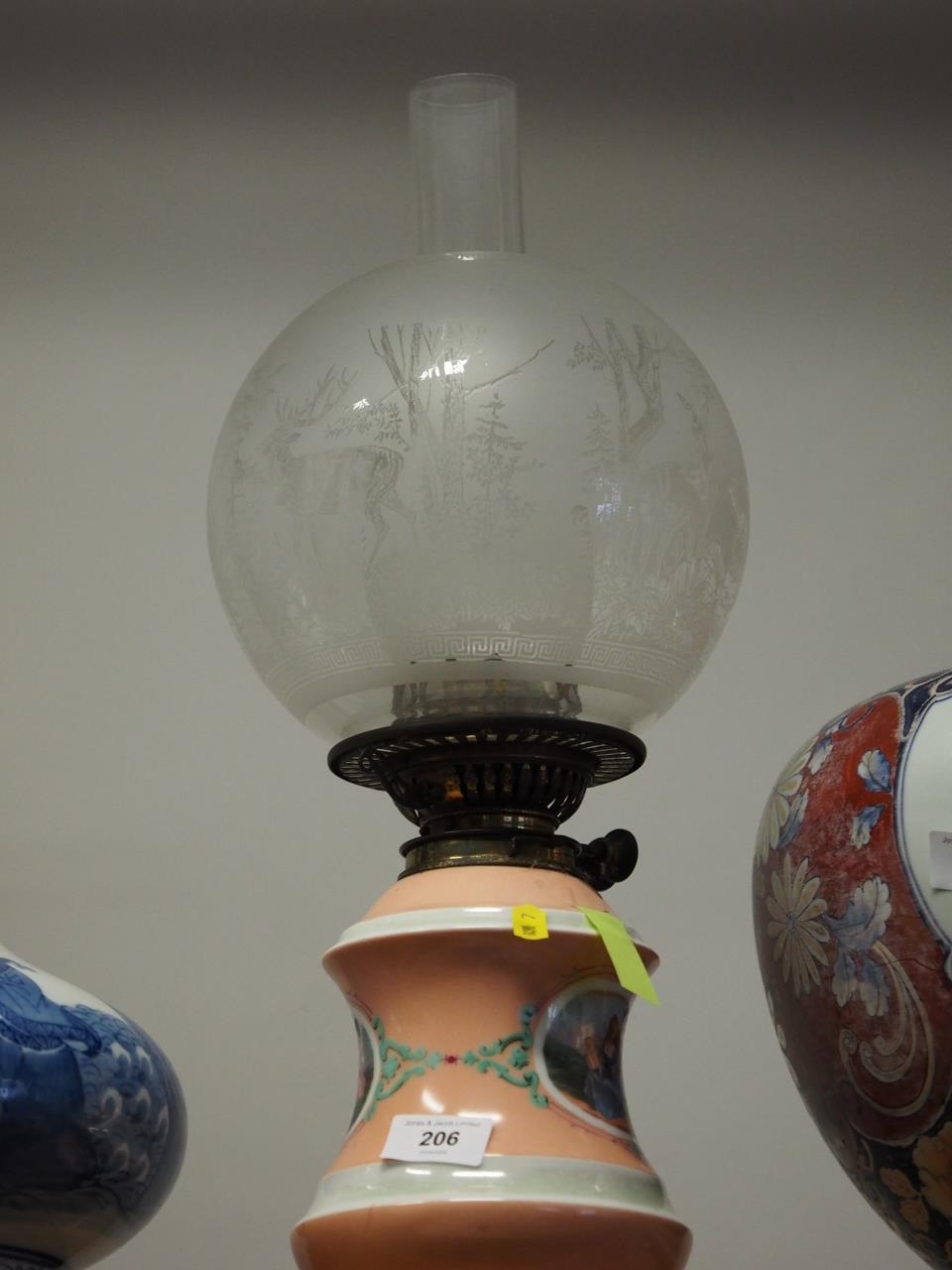 A late 19th century porcelain oil lamp with figure decorated panel, etched shade and chimney, 19"