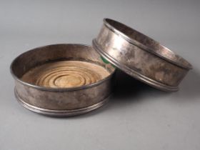 A pair of silver wine bottle coasters with turned wooden bases, 5" dia