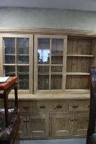 A 19th century waxed pine dresser, the upper section enclosed two glazed doors over three drawers