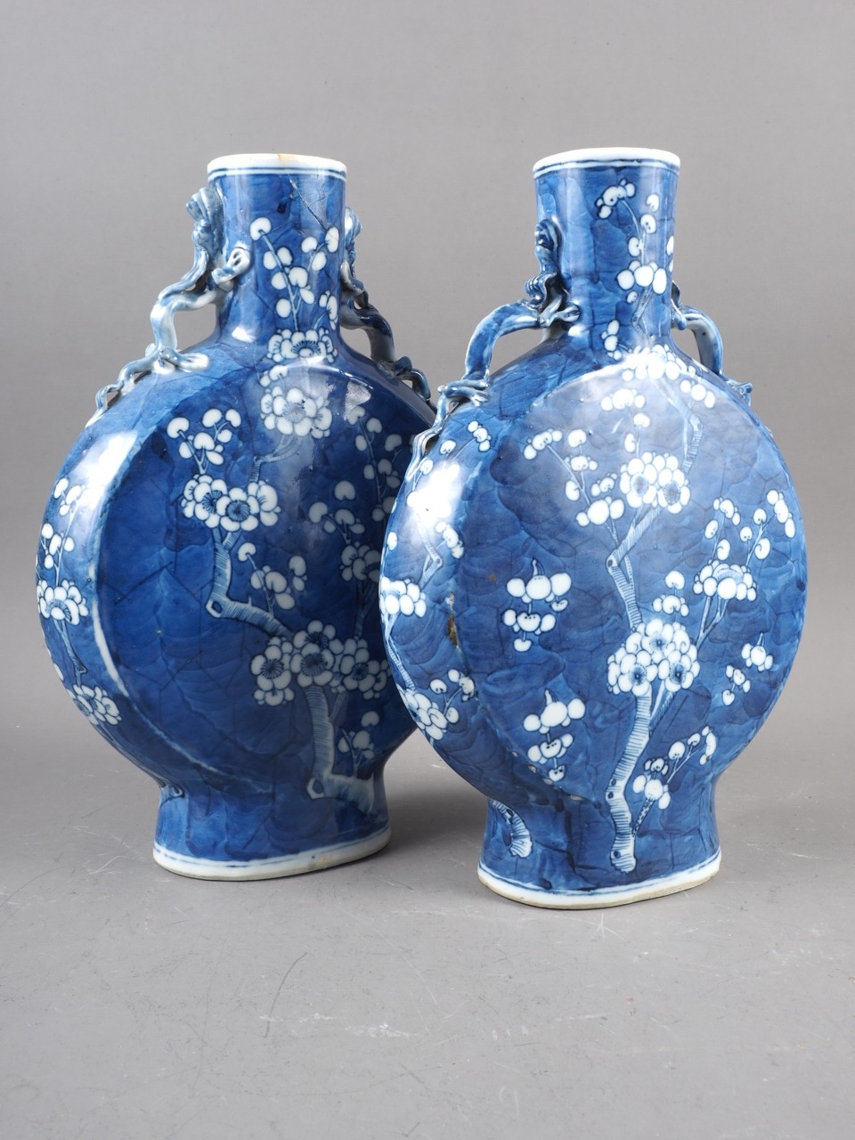 A pair of Chinese blue and white moon flasks with relief dragon handles and prunus decoration,