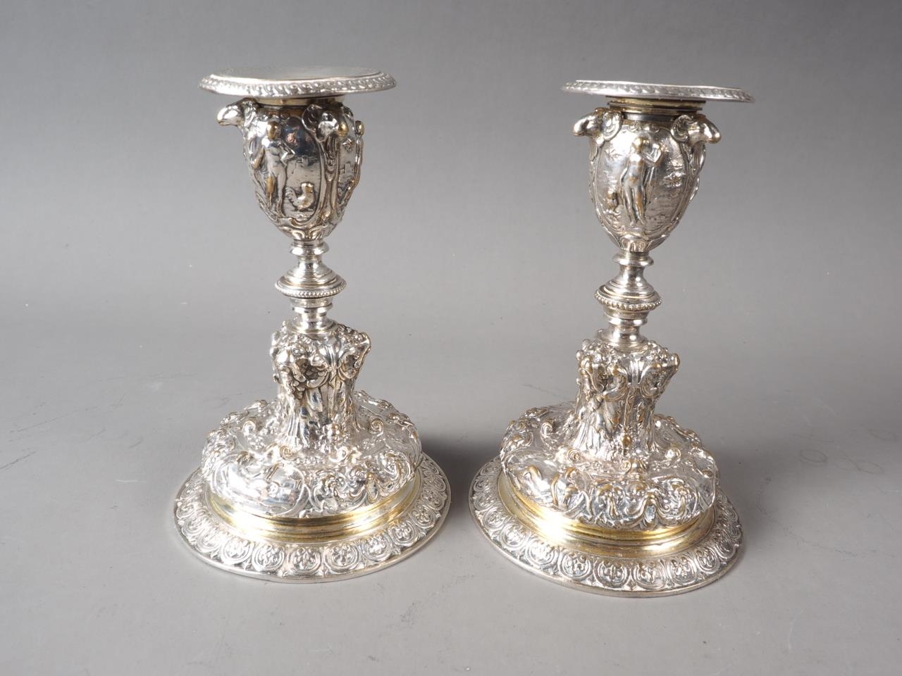 A pair of Elkington silver plated candlesticks with relief and embossed classical decoration, on