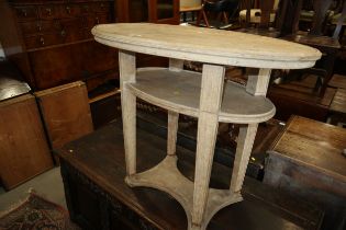 A limed/bleached mahogany oval three-tier occasional table, on square taper supports and plateau